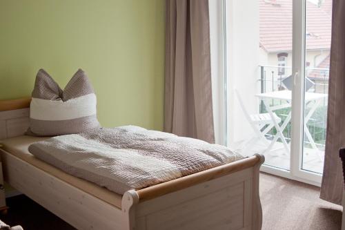a bed with a pillow on it in a room with a window at Cafe Hehrlich - Cafe, Pension & mehr in Bad Tennstedt