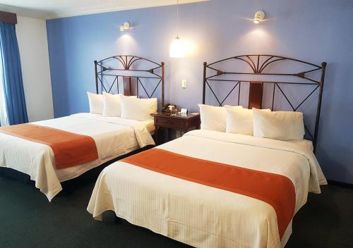 パチューカ・デ・ソトにあるHotel Cirosのブルーウォールのホテルルーム内のベッド2台