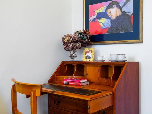 a wooden desk with a chair and a painting on the wall at Apartamenty Magiczny Kraków in Krakow