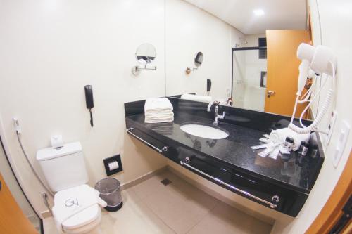 a bathroom with a sink and a toilet and a mirror at Summit Suítes Hotel Caçapava in Caçapava