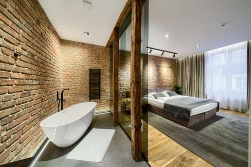 um quarto com uma cama e uma banheira ao lado de uma parede de tijolos em Apartamenty Chełmińskie em Chełmno