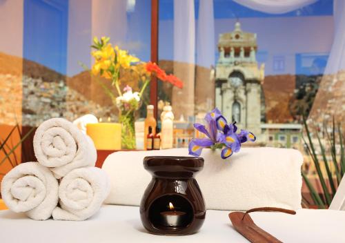 a table with towels and a candle and a room with a clock tower at Hotel Ciros in Pachuca de Soto