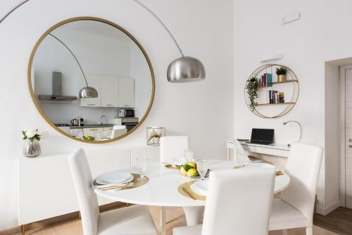 een witte eetkamer met een witte tafel en een spiegel bij Lovely Rome Apartments in Rome