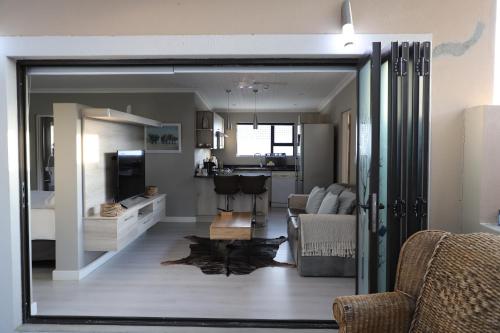 a living room with a sliding glass door leading to a kitchen at Memories Made Cottage in Kampersrus AH