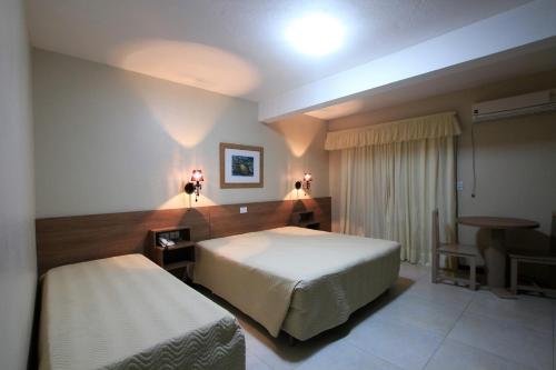 a bedroom with a bed and a table and a desk at Hotel Costa Dalpiaz in Torres