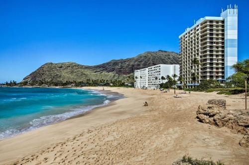 a sandy beach with buildings and the ocean at Stunning Makaha Condo with Pool Access and Ocean View! in Waianae