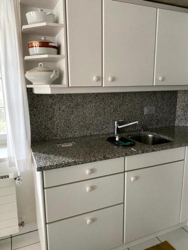 a kitchen with white cabinets and a sink at B&B tannen124 in Oberburg