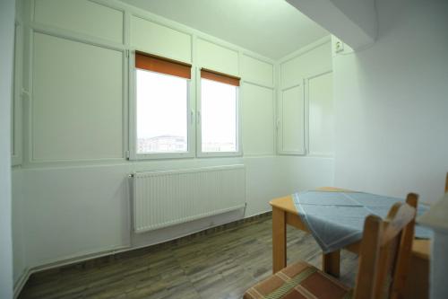 an empty room with a table and two windows at Apartament Alessi in Haţeg