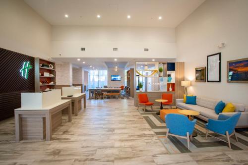 an office lobby with a couch and tables and chairs at Holiday Inn Pensacola - University Area by IHG in Pensacola