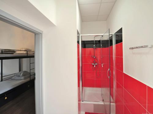a bathroom with a shower with red tile at 3 City Hostel in Gdańsk