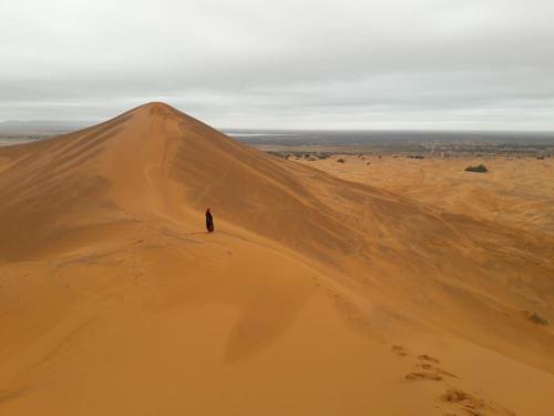 a person standing on a sand dune in the desert at Riad Sephora in Tinerhir