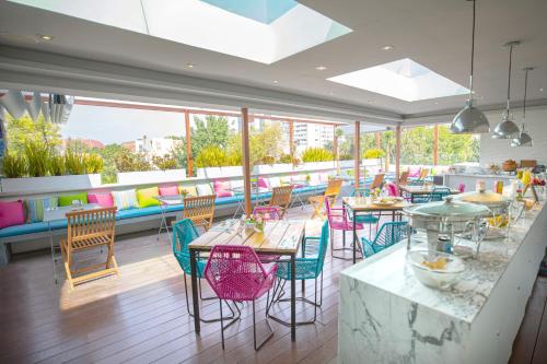 un restaurante con sillas coloridas, mesas y ventanas en Residence L´ Heritage Aristóteles 225 by BlueBay, en Ciudad de México
