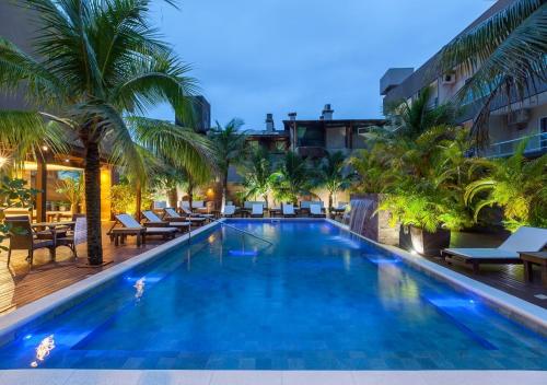 a large swimming pool with palm trees and lounge chairs at Pousada Castellammare in Bombinhas