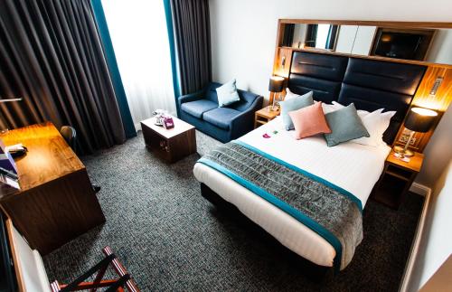 a hotel room with a bed and a chair at Crowne Plaza Leeds by IHG in Leeds