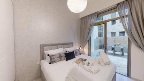 a bedroom with a white bed and a large window at Haneviim Court Luxury by Rental Israel in Jerusalem