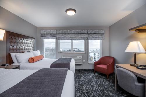 a hotel room with two beds and a chair and a window at The Mediterranean Inn in Seattle