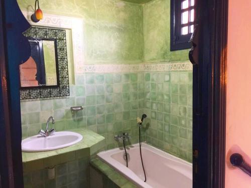 a green tiled bathroom with a sink and a tub at Villa Jardins de la Lagune in Oualidia