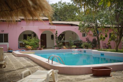 a swimming pool in front of a pink house at Villa Amarant - Private Garden with Pool Retreat in Sanyang