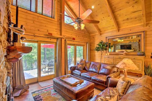 a living room with a leather couch and a ceiling fan at Luxury Mountain Cabin with Furnished Deck and Views! in Loma Linda