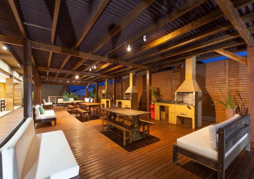a living room with tables and benches on a wooden floor at Pousada Castellammare in Bombinhas