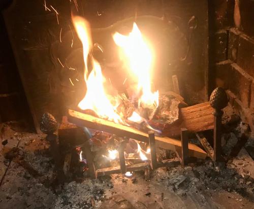 a fire in a fireplace with a bench in front of it at Maison d'hoursentut in Sainte-Marie-de-Campan