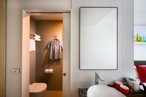 a bathroom with a toilet and a mirror at ibis Melbourne Central in Melbourne