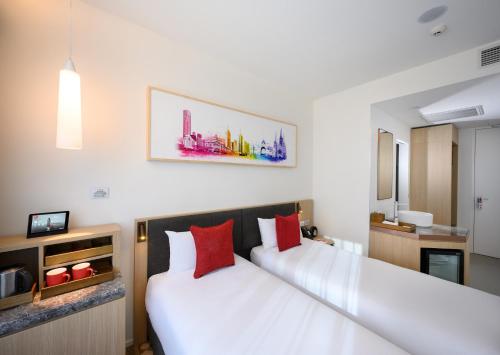 two beds in a hotel room with red pillows at ibis Melbourne Central in Melbourne