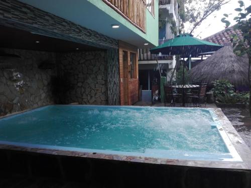 a large pool of water with a table and an umbrella at Spa Posada 4 Esquinas in La Uvita