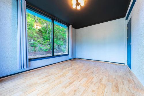 an empty room with two windows and a wooden floor at Hooni Guest House & Motel in Gurye