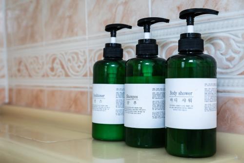 three green bottles sitting on a counter in a bathroom at Hooni Guest House & Motel in Gurye