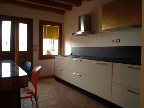a kitchen with white cabinets and a table and a stove at Casa delle Bruscole in Conegliano