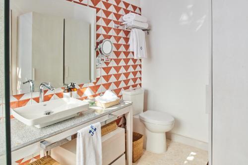 a bathroom with a sink and a toilet and a mirror at Hotel Luxury Patio Azul in Puerto Vallarta