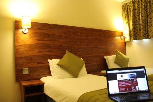 a hotel room with a laptop computer on a bed at Stockwood Hotel - Luton Airport in Luton