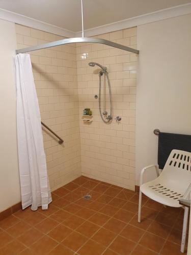 a bathroom with a shower with a white shower curtain at The Lancefield Lodge in Lance Field