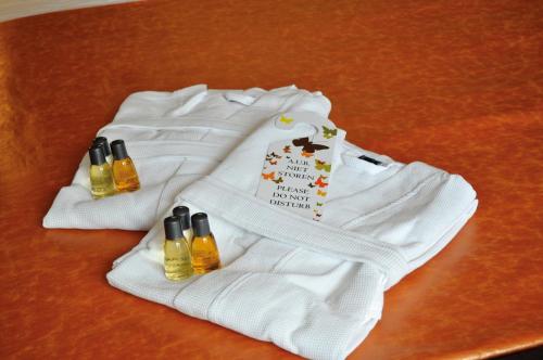 dos jerseys blancos y tres botellas de aceites esenciales sobre una mesa en City Hotel Koningsvlinder en Veenendaal