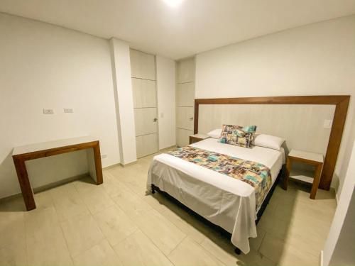 a bedroom with a bed and two tables in it at Hotel Santorini in Guatapé