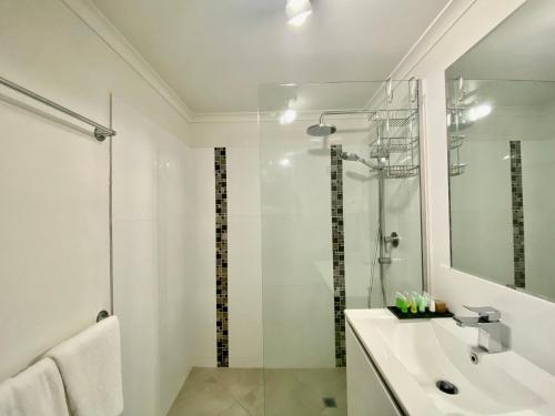 a white bathroom with a sink and a shower at Cairns Beach Resort in Cairns