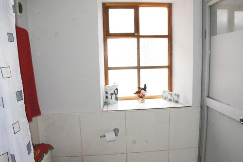 Baño con ventana con un juguete en un estante en Trinidad wasi, en Cusco