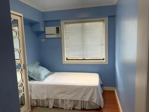 a blue room with a bed and a window at Northpoint Camella Condo Suites in Davao City