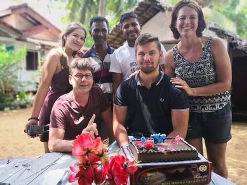 a group of people standing around a table with a cake at Star Rest Beach Hotel in Arugam Bay