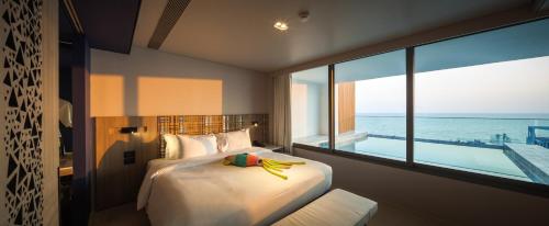 a bedroom with a bed with a view of the ocean at Veranda Resort Pattaya - MGallery by Sofitel in Jomtien Beach