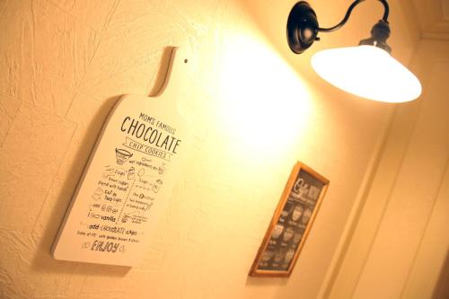 a sign hanging on a wall with a light at Hotel 3 O'Clock Tennoji in Osaka
