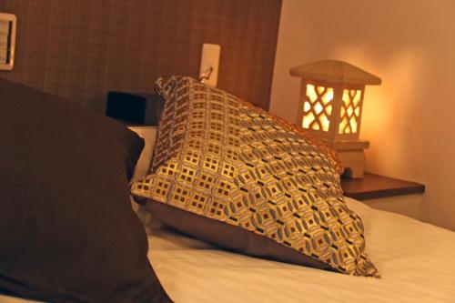 a pillow on top of a bed with a lamp at Hotel 3 O'Clock Tennoji in Osaka