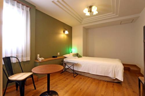 a bedroom with a bed and a table and chair at Hotel 3 O'Clock Tennoji in Osaka