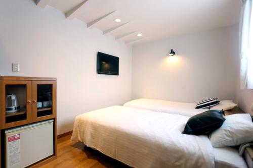 a bedroom with two beds and a tv on the wall at Hotel 3 O'Clock Tennoji in Osaka