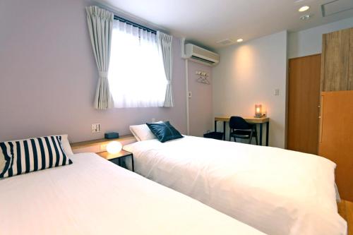 大阪市にあるHotel 3 O'Clock Tennojiのベッド2台と窓が備わるホテルルームです。