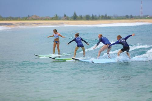 a group of people riding surfboards in the ocean at Star Rest Beach Hotel in Arugam Bay