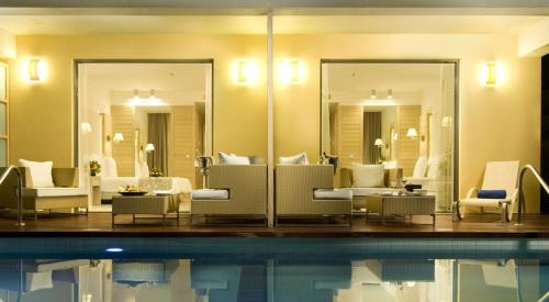 a hotel lobby with a pool and mirrors at Astir Odysseus Kos Resort and Spa in Tigaki