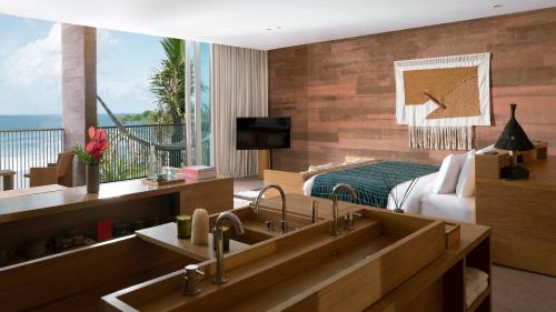 a bathroom with a sink and a bedroom with a bed at Potato Head Suites & Studios in Seminyak