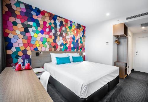 a bed room with a painting on the wall at ibis Styles Brisbane Elizabeth Street in Brisbane